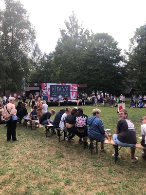 Eröffnungsabend vom IFM. Leute sitzen auf Bierbänken vor der Bühne auf der ein Banner mit dem IFM Logo hängt